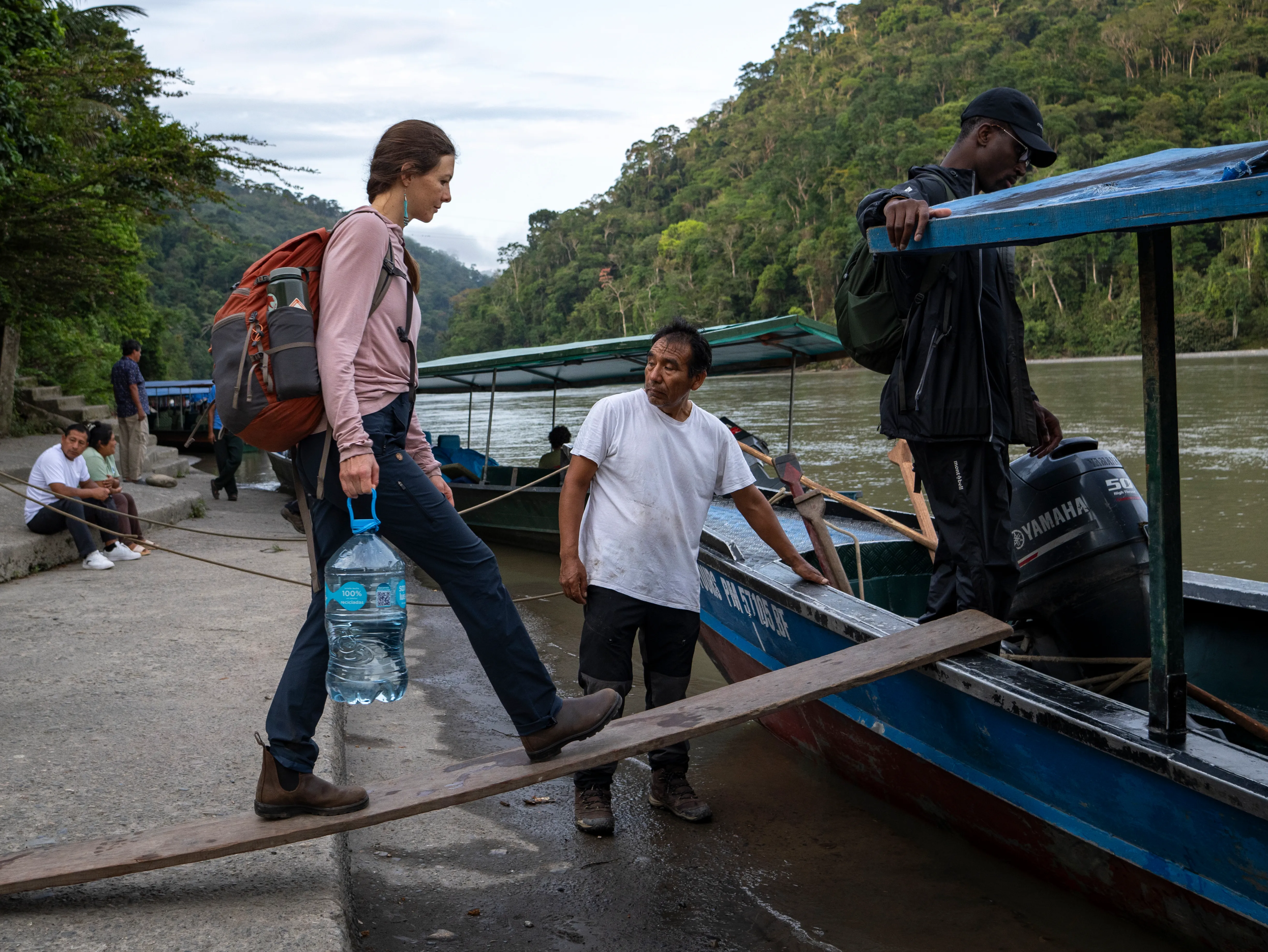 A man wearing blue latex gloves in a white laboratory, looking through a microscope